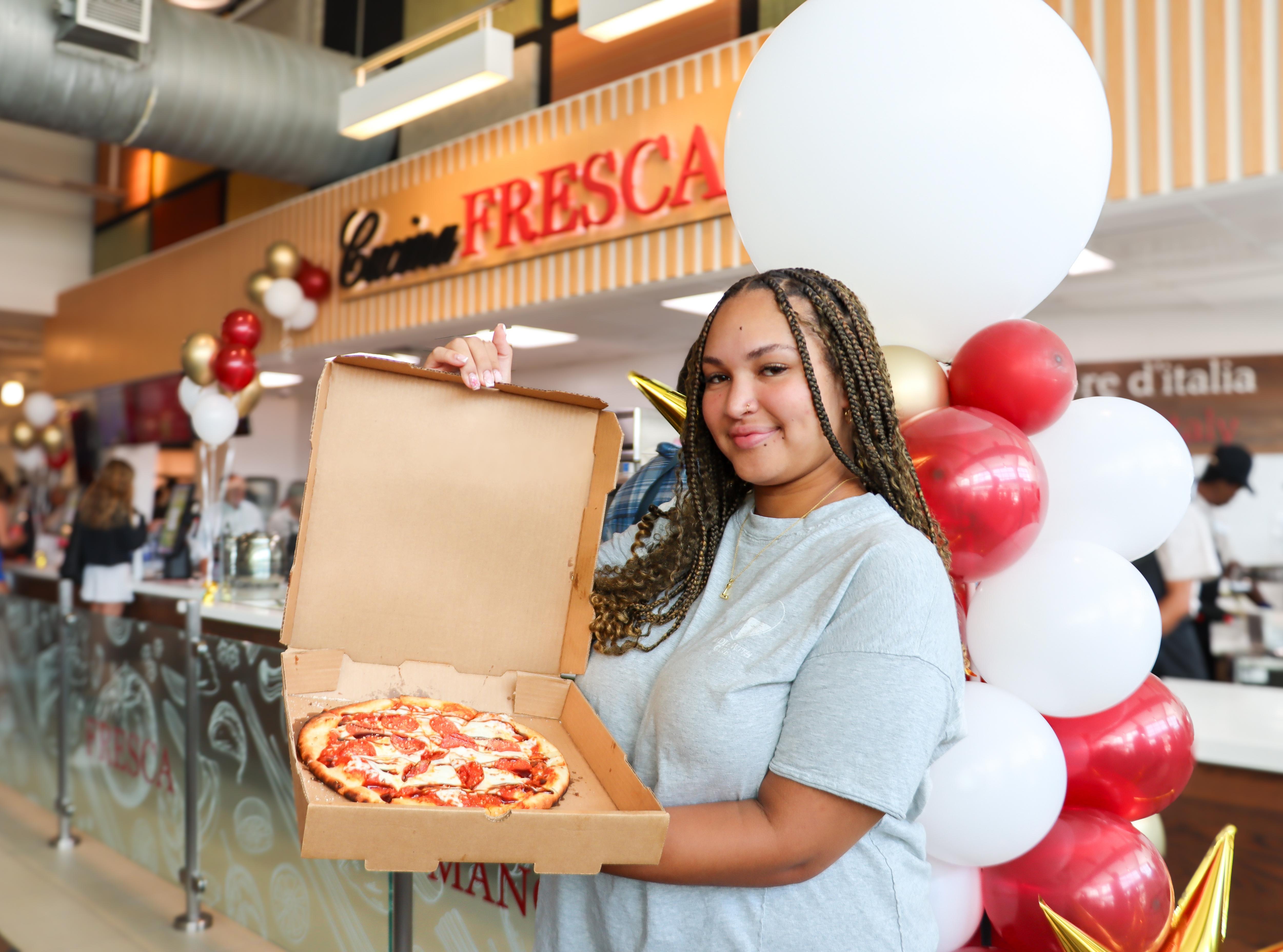 Student holding a pizza at a campus dining launch